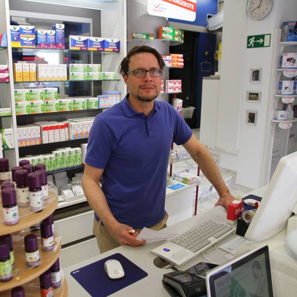 Es ist der Apotheker Marc Remmel zu sehen, wie er hinter seinem Tresen steht.