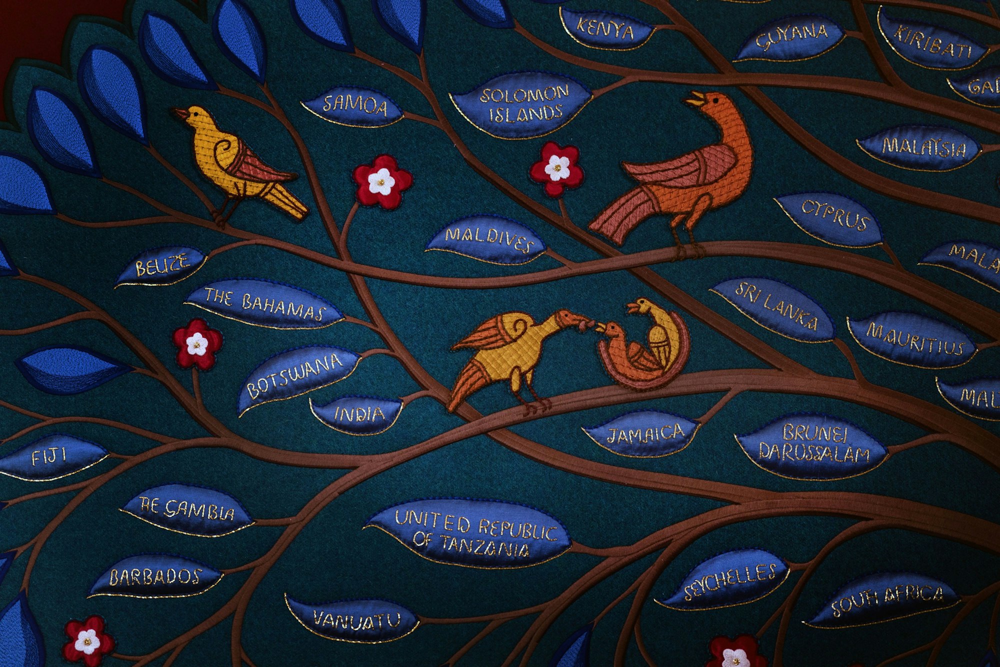 24.04.2023, Großbritannien, London: Detail der Namen einiger Commonwealth-Länder, die von der Royal School of Needlework auf den Salbungsschirm genäht wurden, der bei der Krönung von König Charles III. von Großbritannien verwendet wird und in der Chapel Royal im St. James's Palace in London steht.