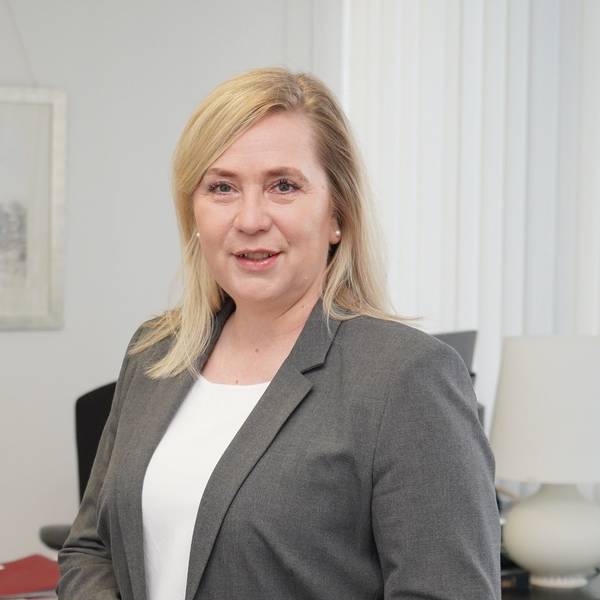 Auf dem Foto ist ein Portrait von Frechens Bürgermeisterin Susanne Stupp zu sehen, sie trägt ein weißes T-Shirt und ein graues Sakko.