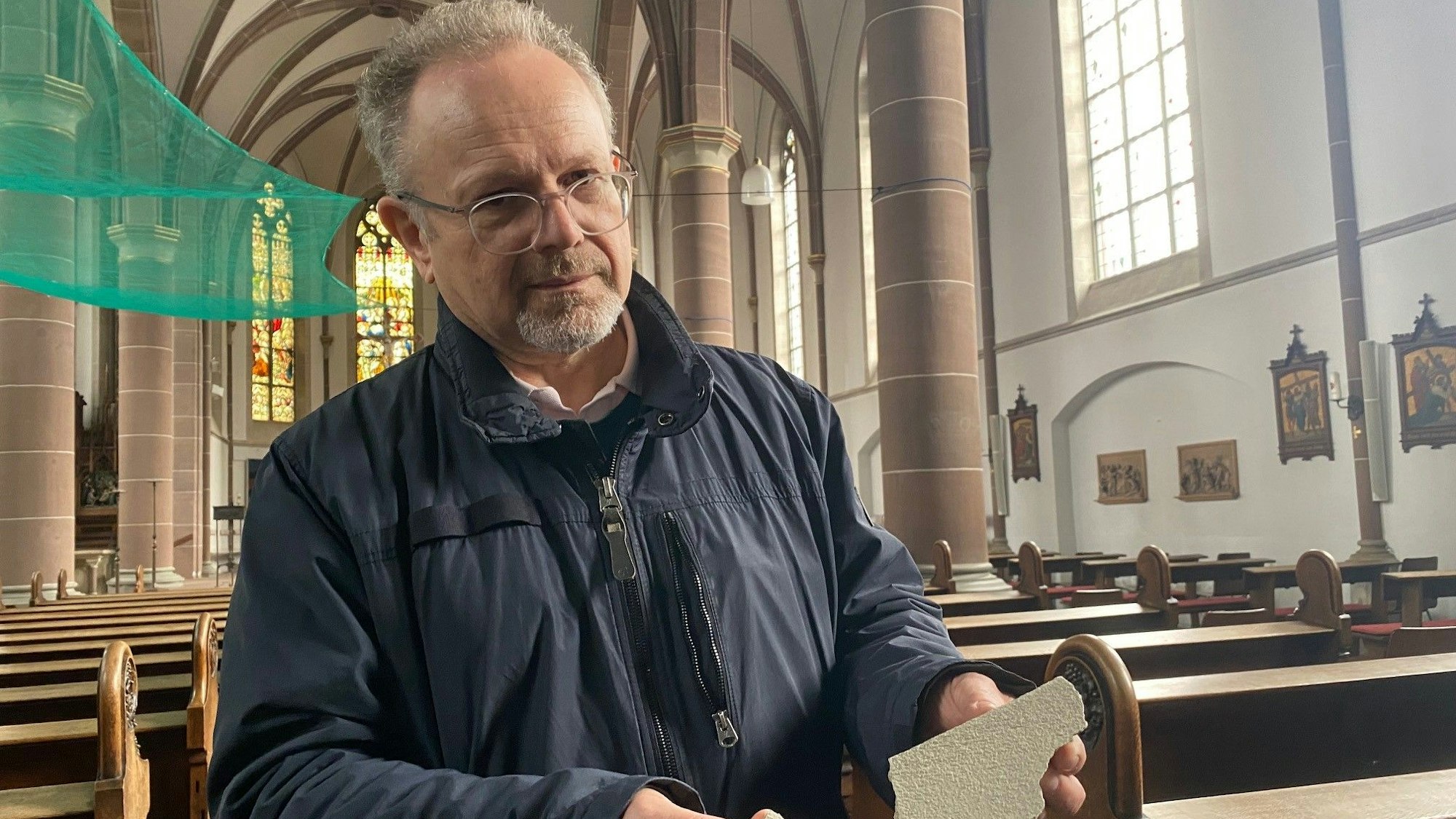 Manfred Bäuml hält die zwei Stücke Putz in der Hand, die sich von einem Gewölbe gelöst haben.