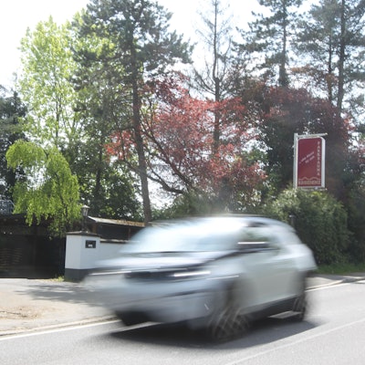 Ein rotes Schild steht an einer von einer weißen Mauer umrahmten Einfahrt.