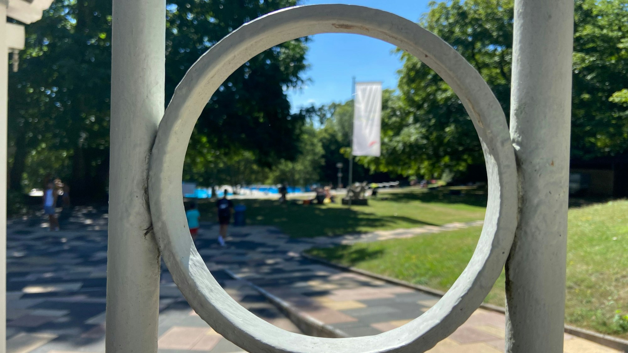 Auf dem Bild ist ein Blick in das Freibad durch den Zaun am Eingangsbereich zu sehen.