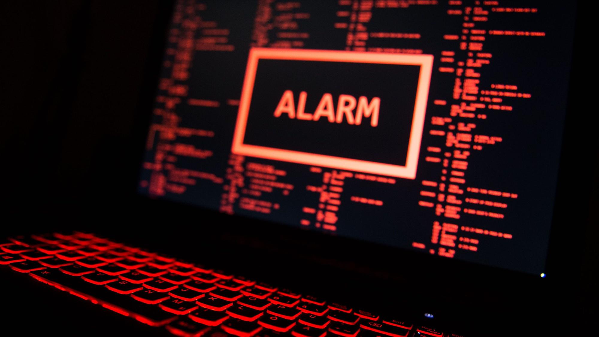 Ein rot beleuchteter Computer zeigt eine fiktive Fehlermeldung an (gestellte Szene).