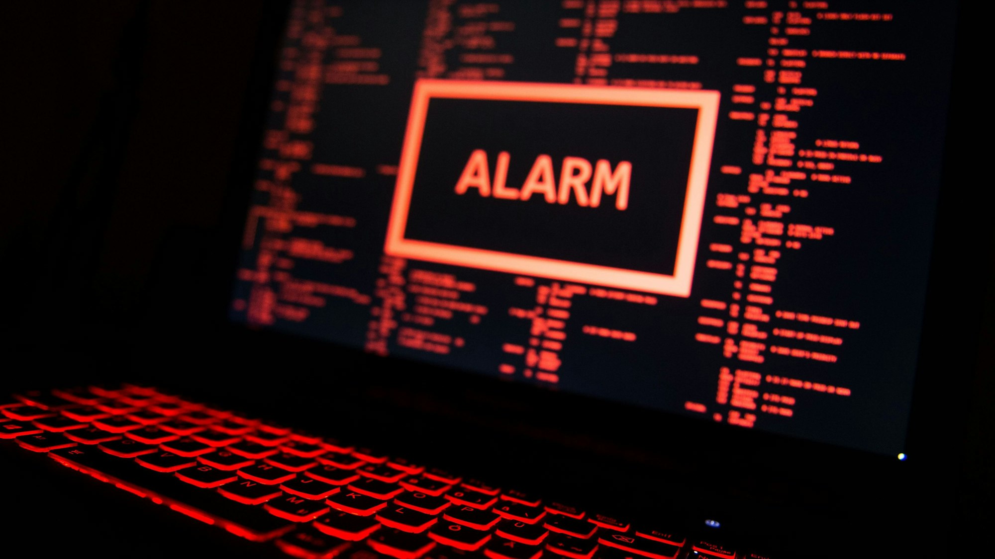 Ein rot beleuchteter Computer zeigt eine fiktive Fehlermeldung an (gestellte Szene).