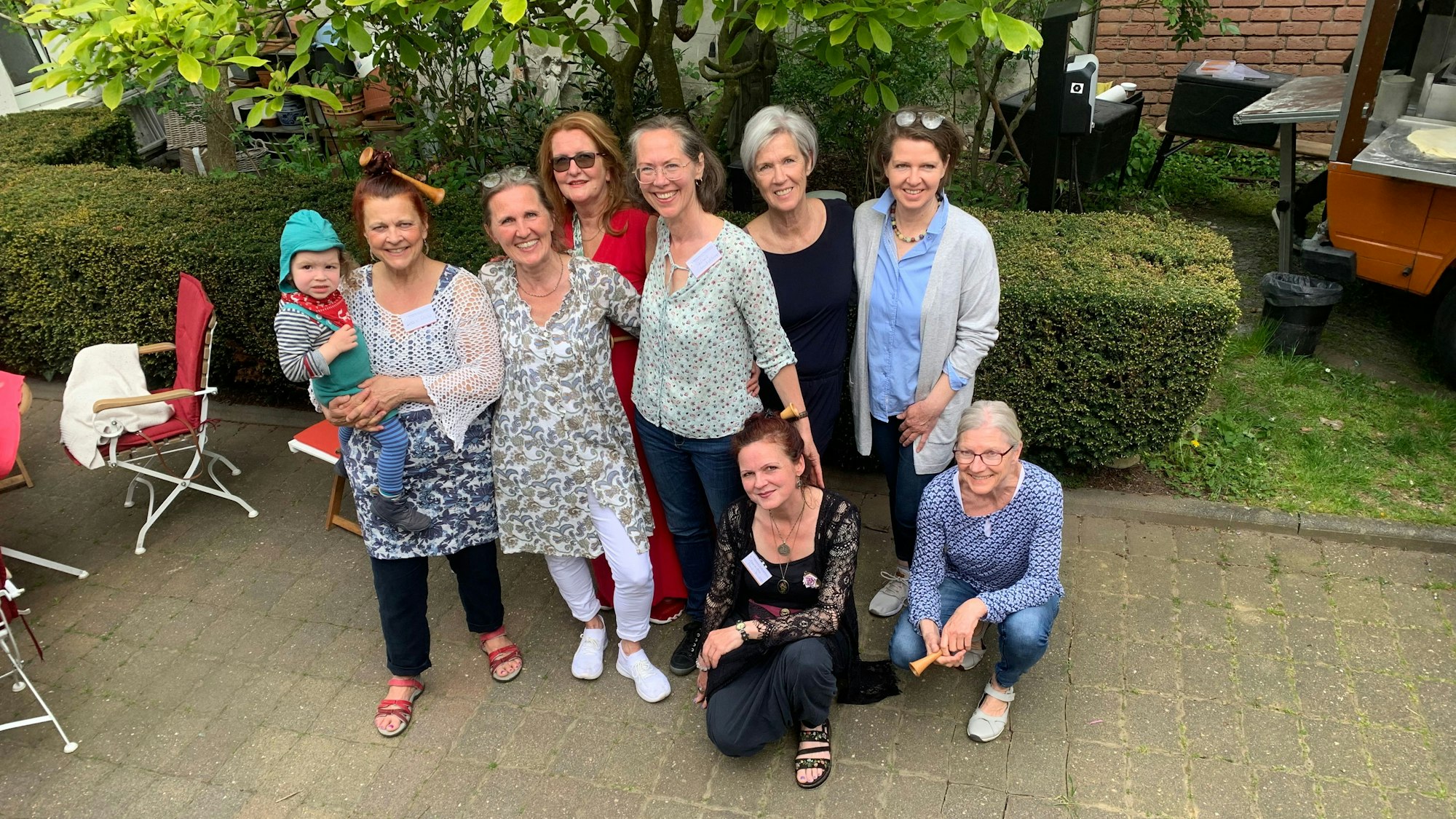 Das Gründungsteam des Hebammenhauses steht zusammen vor einer Hecke.