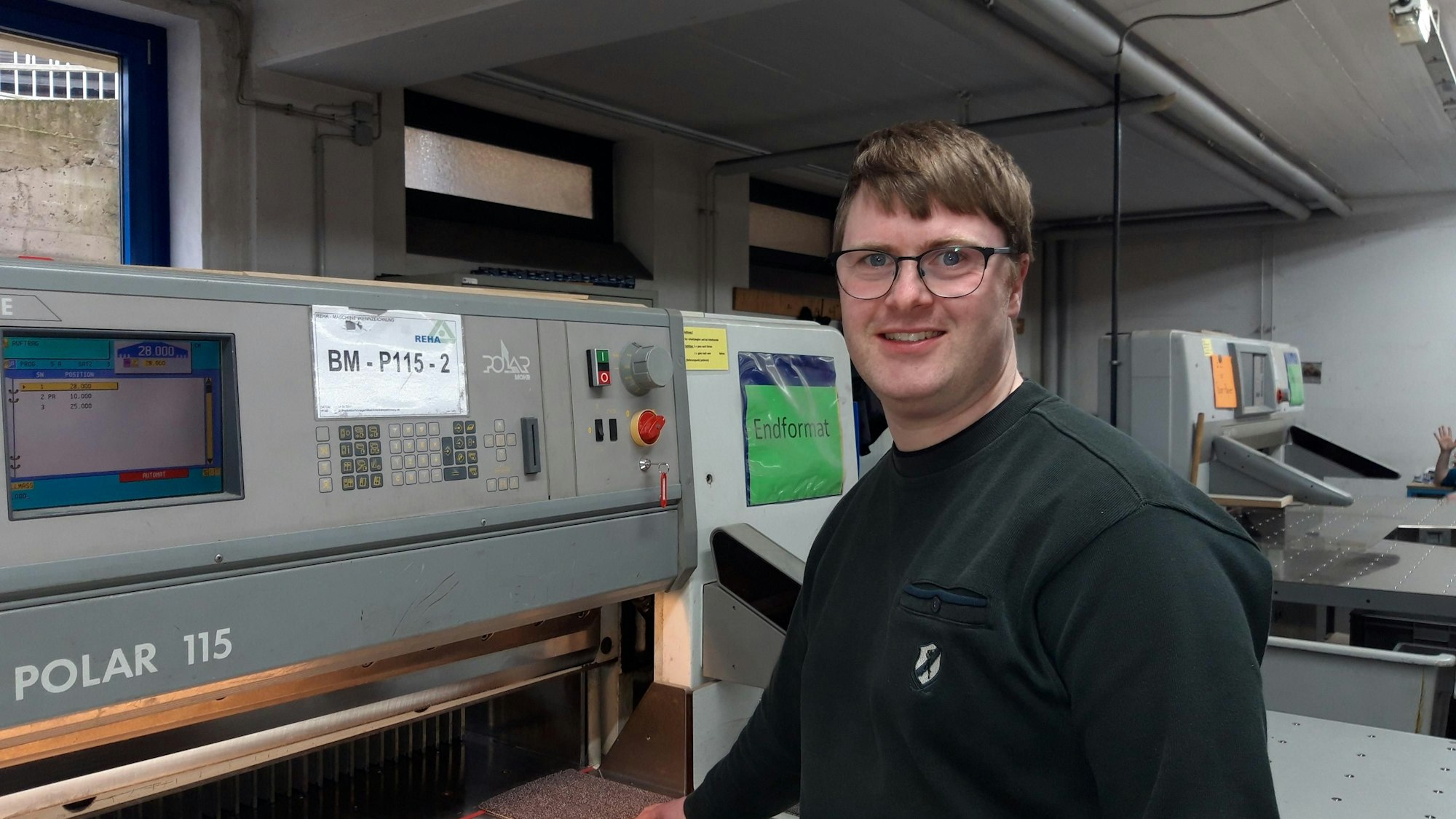 Ansgar Peters steht vor einer Polarschneidemaschine.