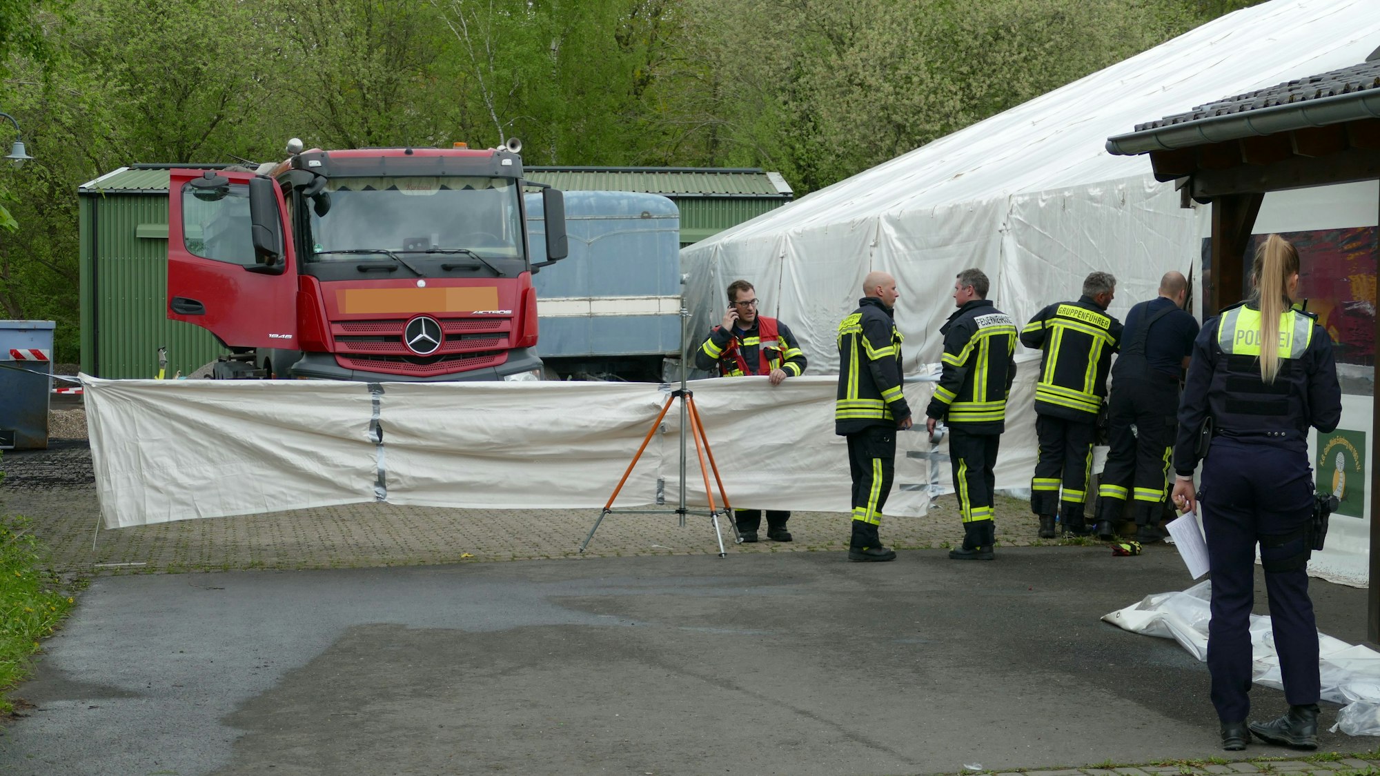 Feuerwehrleute stehen rund um einen Sichtschutz an einer Unglückstelle.