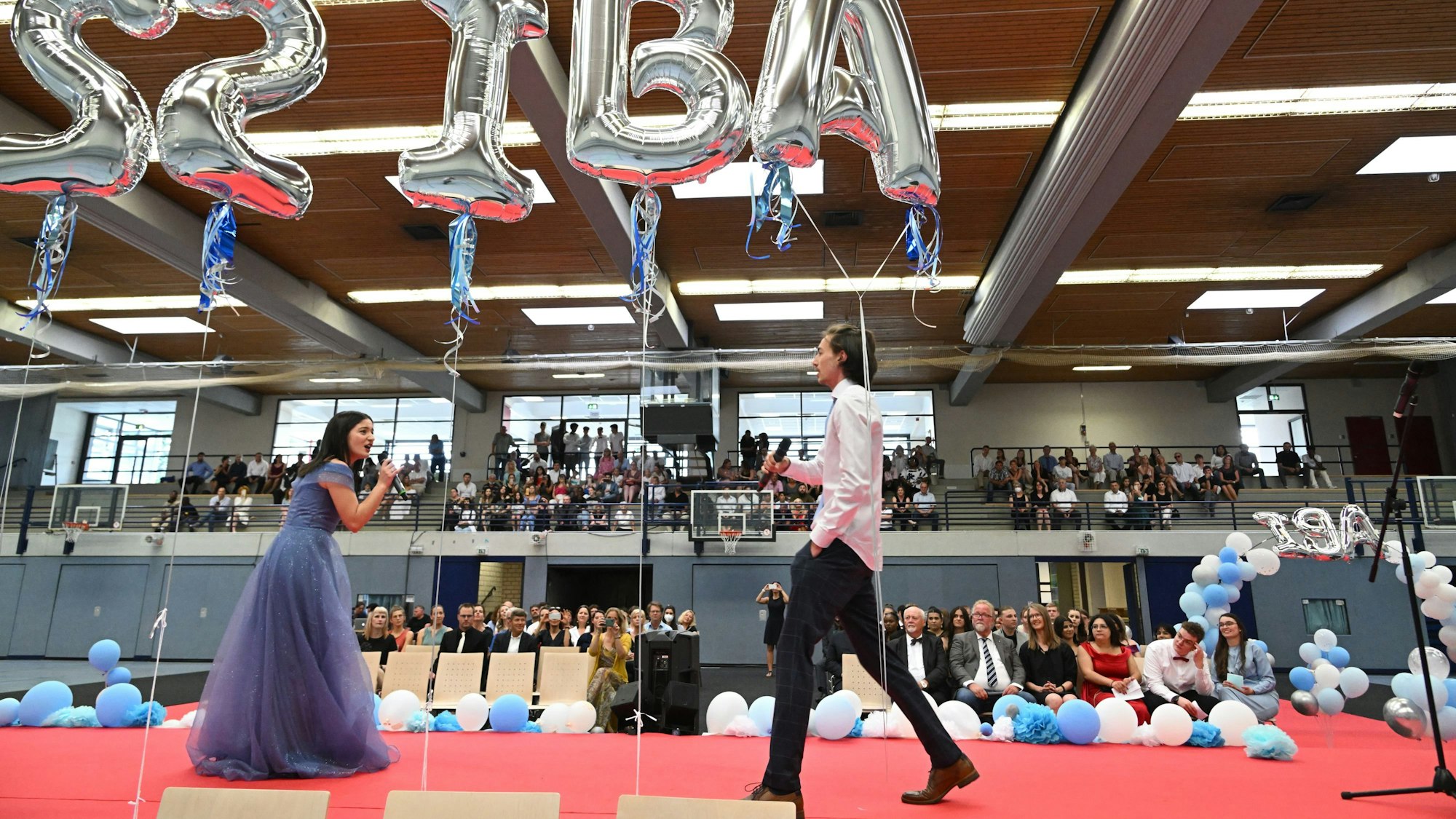 Zwei Schüler des Abi-Jahrgangs stehen auf der Bühne und singen.