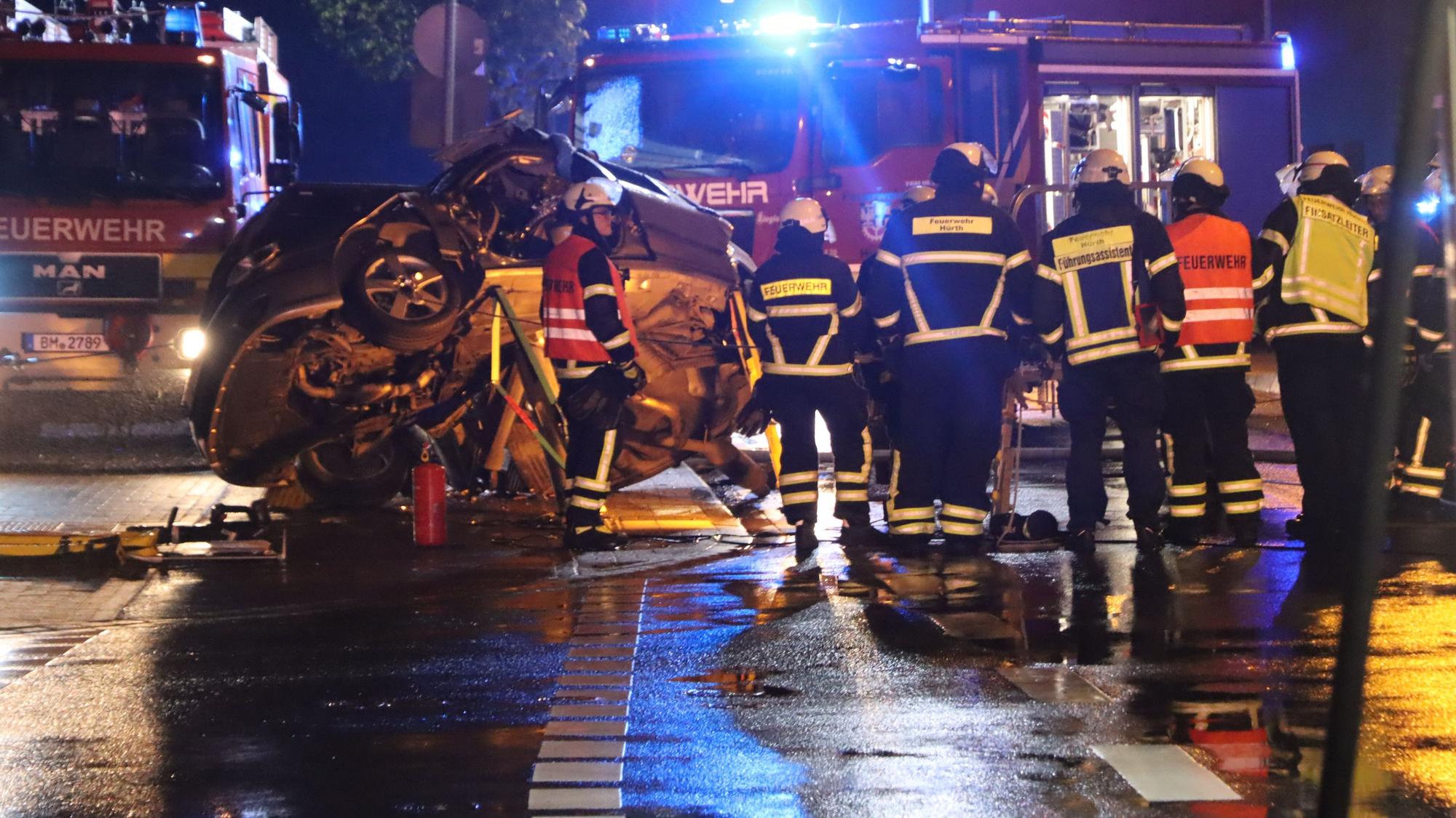 Das Foto zeigt Feuerwehrleute und Ersthelfer vor dem Wrack. Im Hintergrund sind Rettungsfahrzeuge zu sehen.