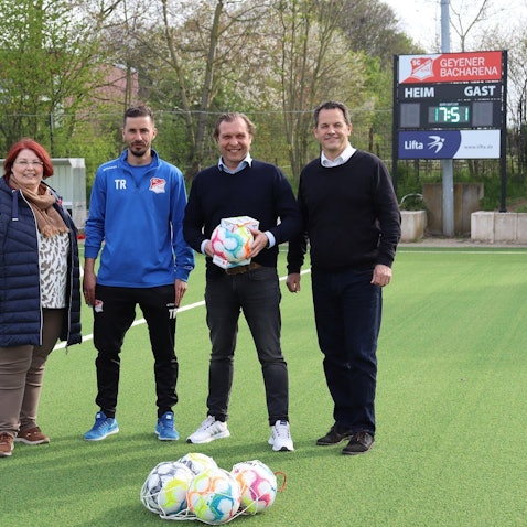 Ortsvorsteherin Birgitt Baus, Jugendleiter Dennis Frère, Patrick Gartmann, Vorsitzender des SC Germania 1932 Geyen und Bürgermeister Frank Keppeler stehen auf dem Kunstrasenplatz.