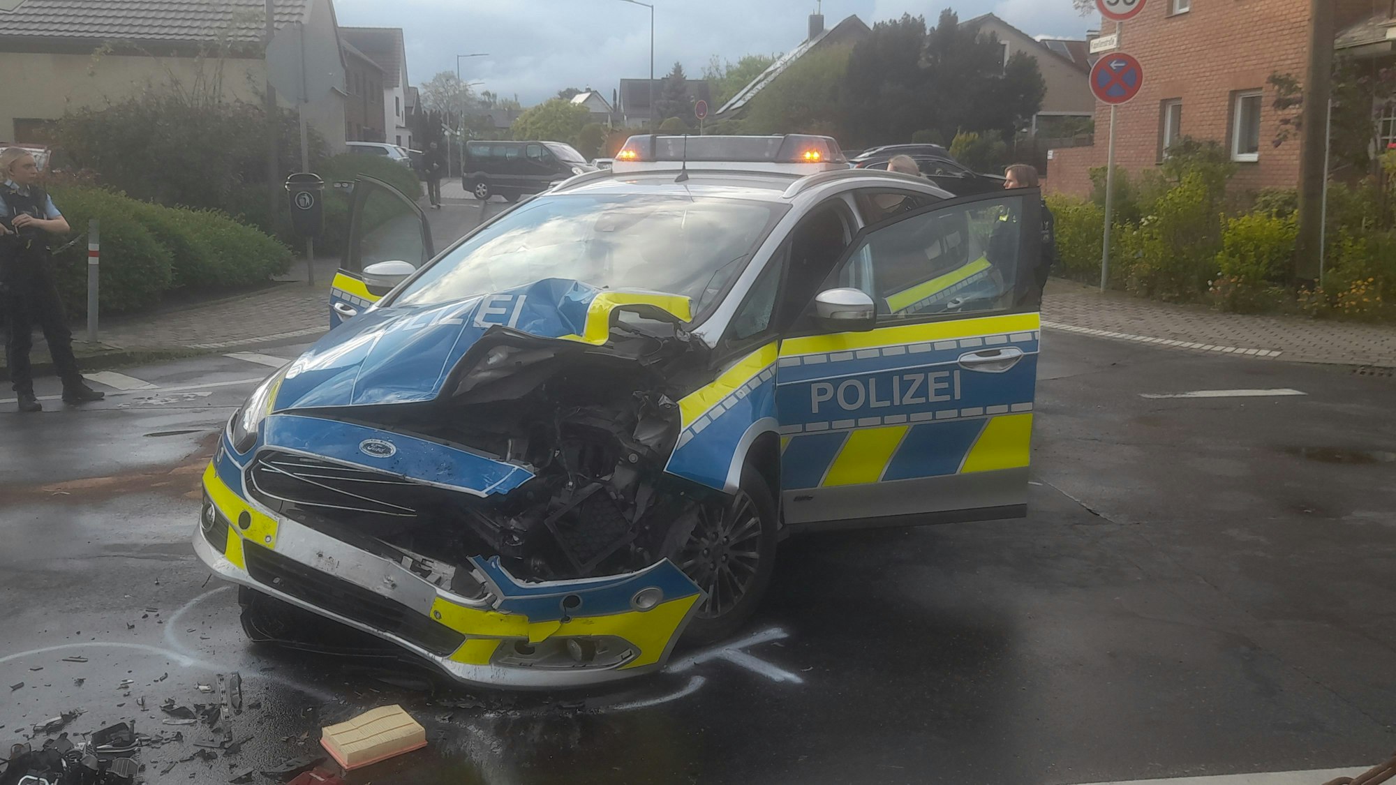 Ein Polizeiauto steht schwer beschädigt auf einer Kreuzung. Die linke Fron des Wagens ist aufgerissen und zerbeult.