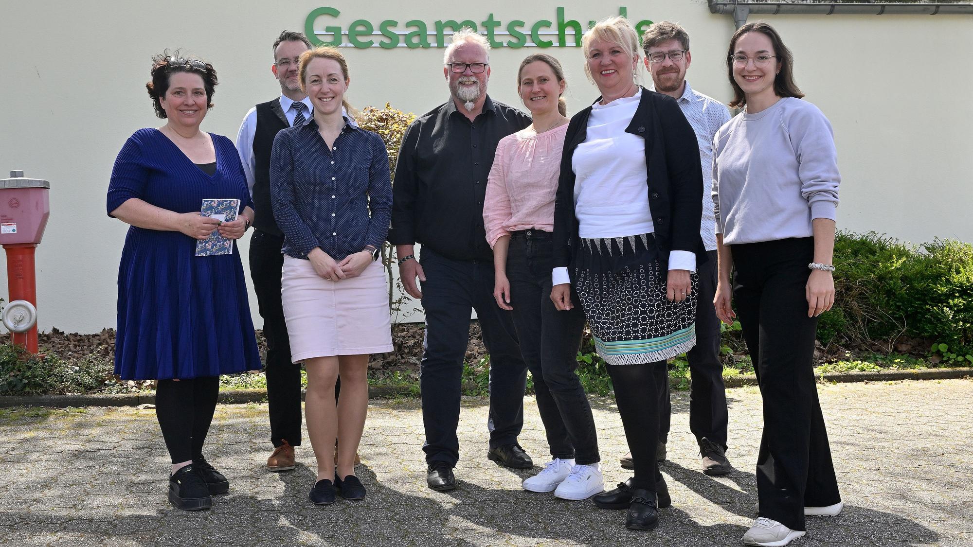 Das Jury-Team posiert vor der Schule und lächelt in die Kamera.