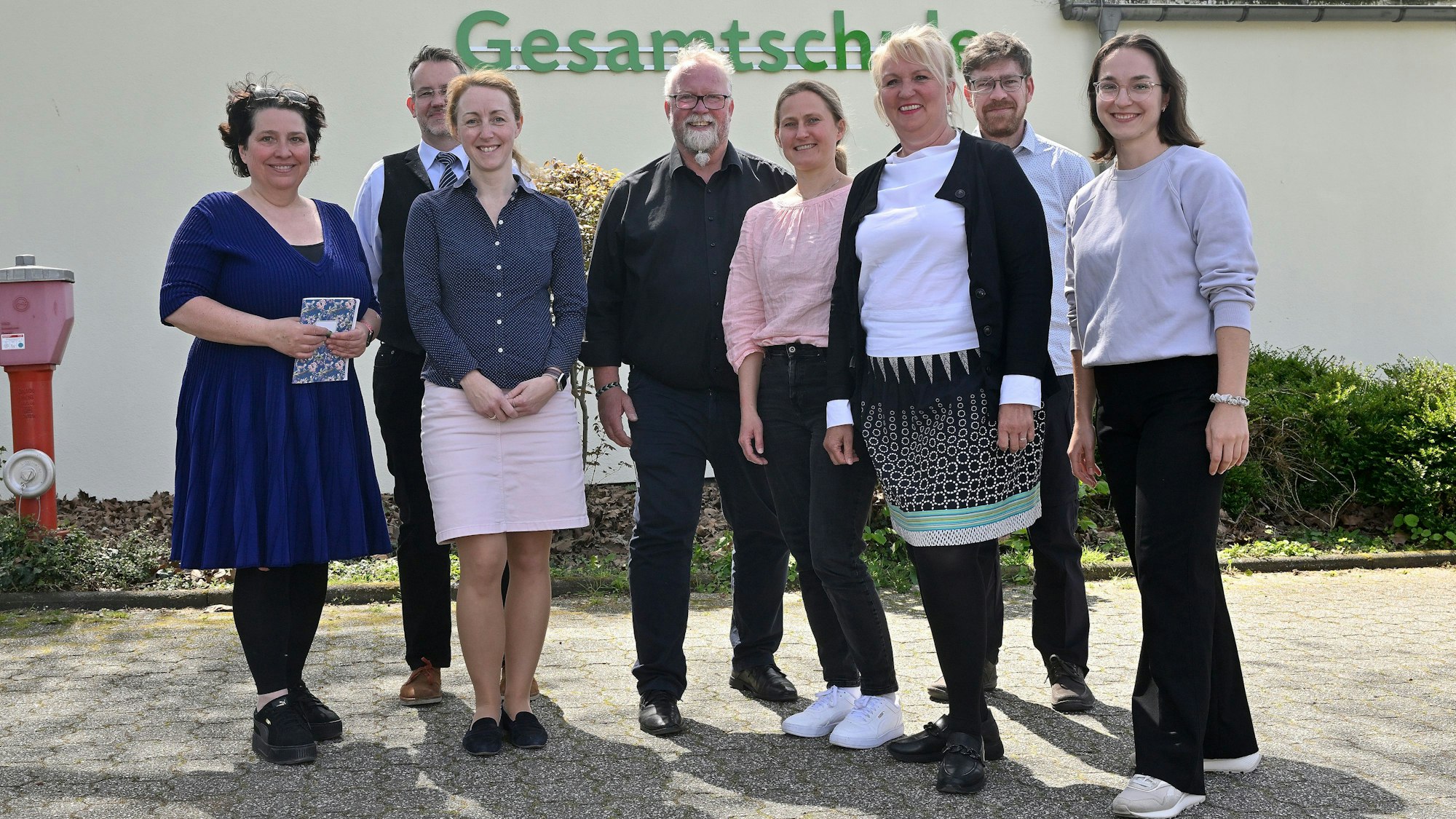 Das Jury-Team posiert vor der Schule und lächelt in die Kamera.