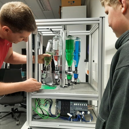 Ein Mann hantiert mit Flaschen, die in einer Apparatur eingespannt sind.