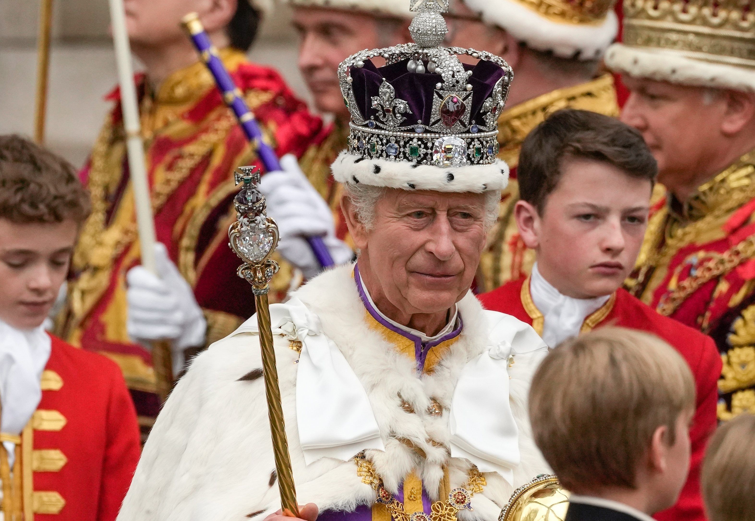König Charles III. verlässt nach der Krönungszeremonie mit der Imperial State Crown, einem Zepter und dem Reichsapfel die Westminster Abbey.