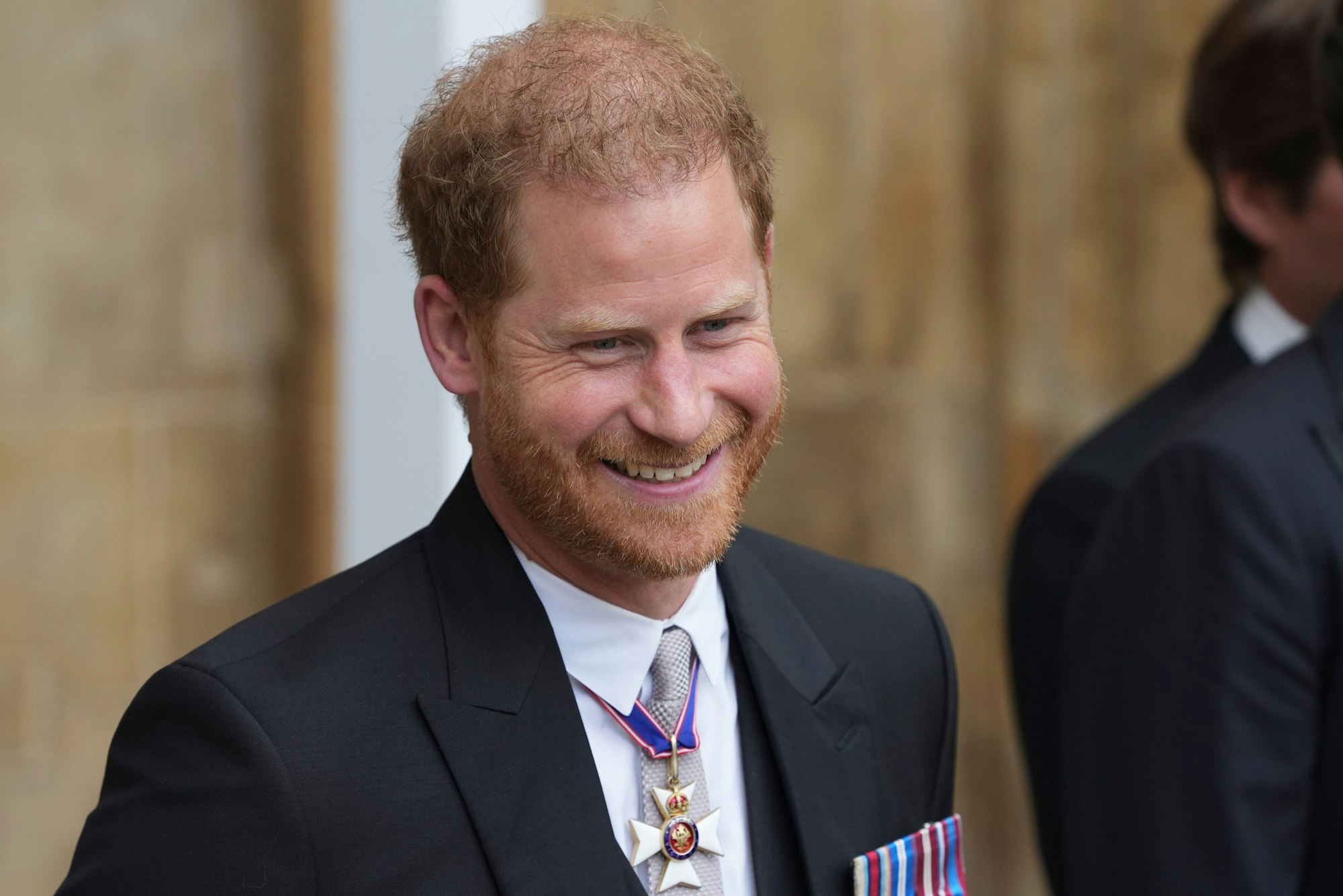London: Prinz Harry, Herzog von Sussex, verlässt nach der Krönung von König Charles III. und Königin Camilla die Westminster Abbey und lächelt.