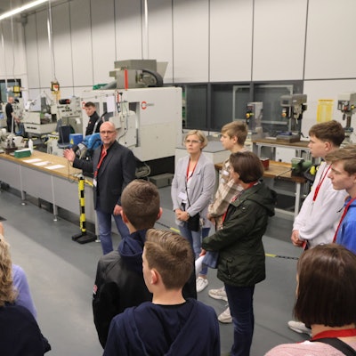 Ein Mann führt eine Gruppe durch die Produktionshallen eines Unternehmens.