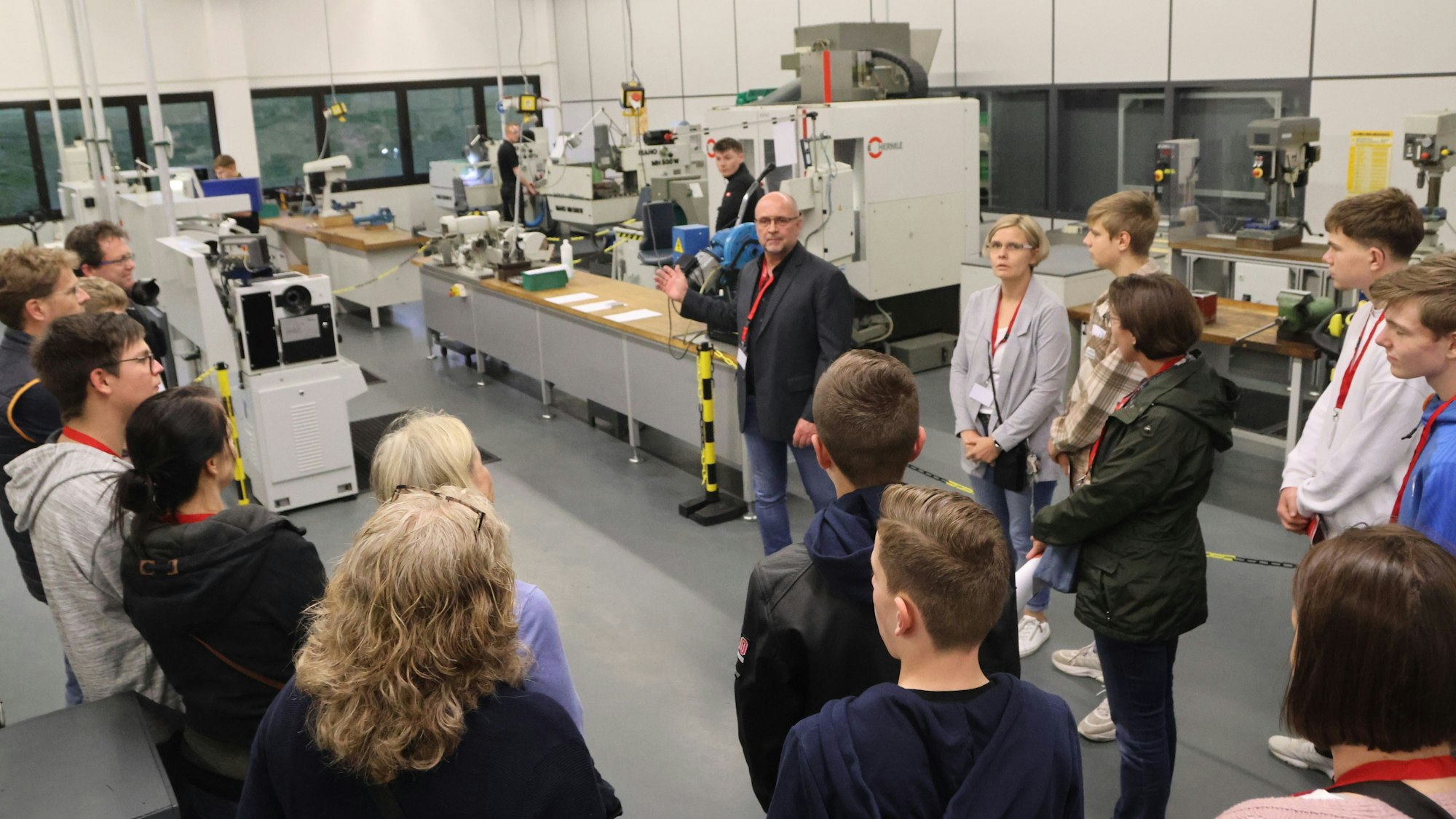 Ein Mann führt eine Besuchergruppe durch die Werkstatt eines Unternehmens.