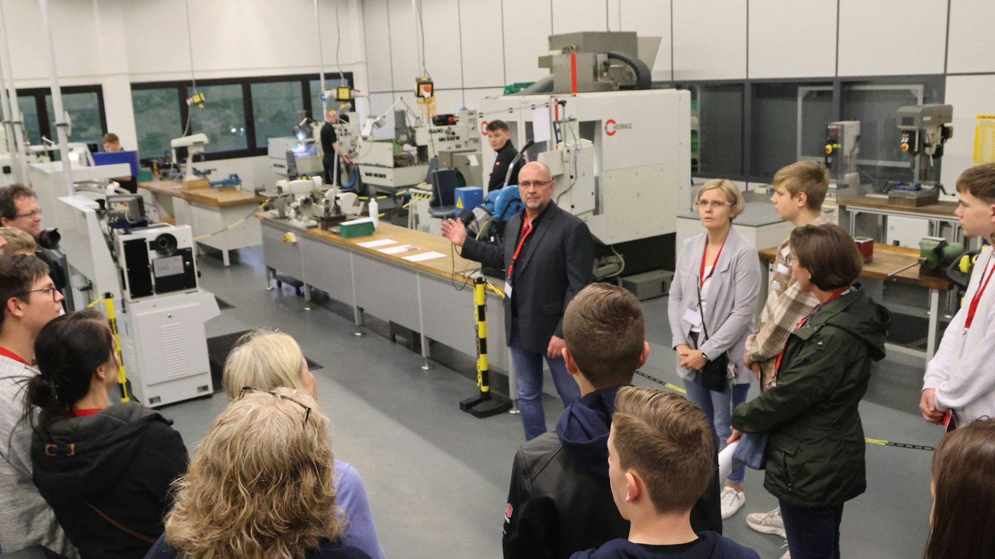 Bei der Nacht der Technik führt der Sarstedt-Mitarbeiter Andreas Fiedler eine Besuchergruppe durch eine mit Maschinen gefüllte Ausbildungswerkstatt.