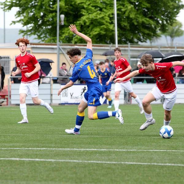Ein Spieler der JSG Erft 01 im roten Trikot und weißer Hose lässt einen Spieler des 1. FC Düren II ganz in blau aussteigen.