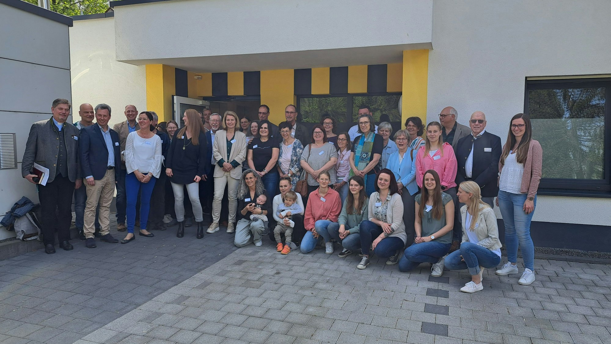 Vor dem Gebäude stehen Helfer und Helferinnen bei der Einweihung.