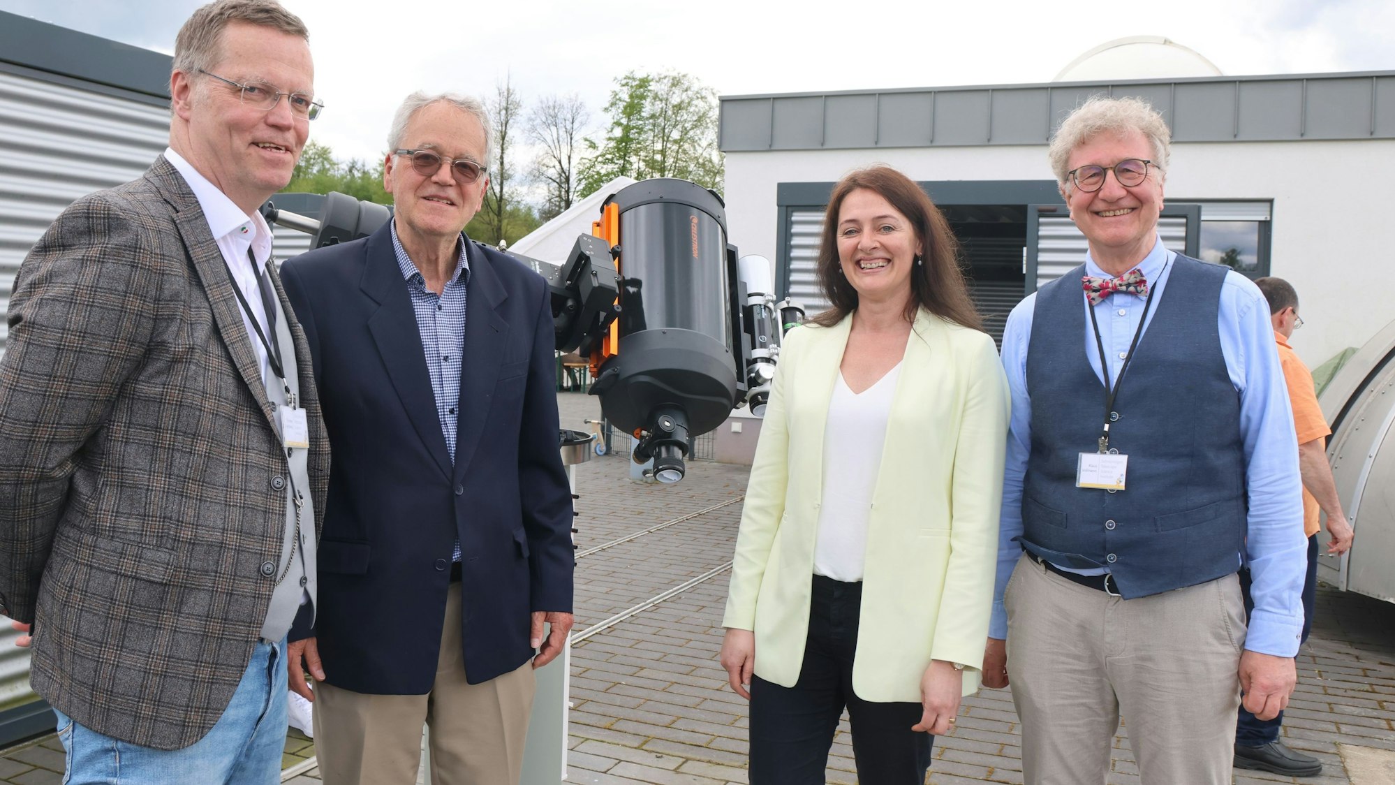 Zu sehen sind drei Männer und eine Frau mit einem großen Teleskop.