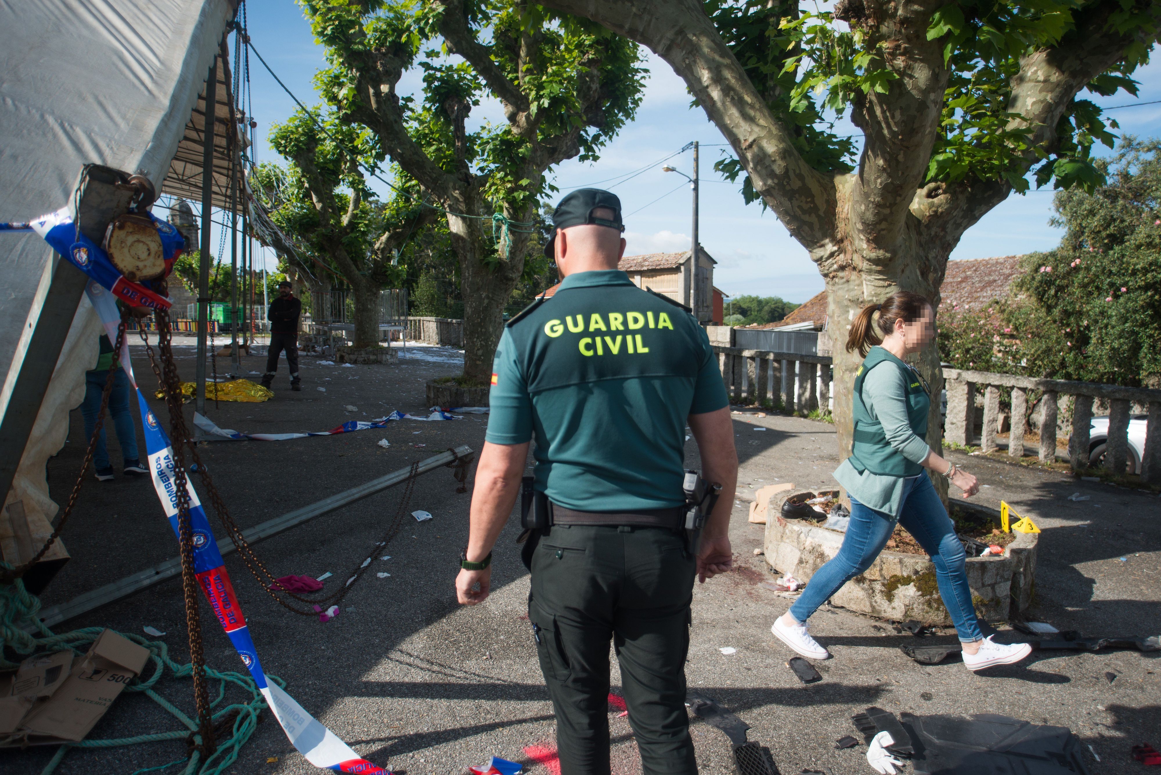 Neben einem Festzelt liegen Banner und Beamte der Guardia Civil gehen das Gelände mit Bäumen ab.