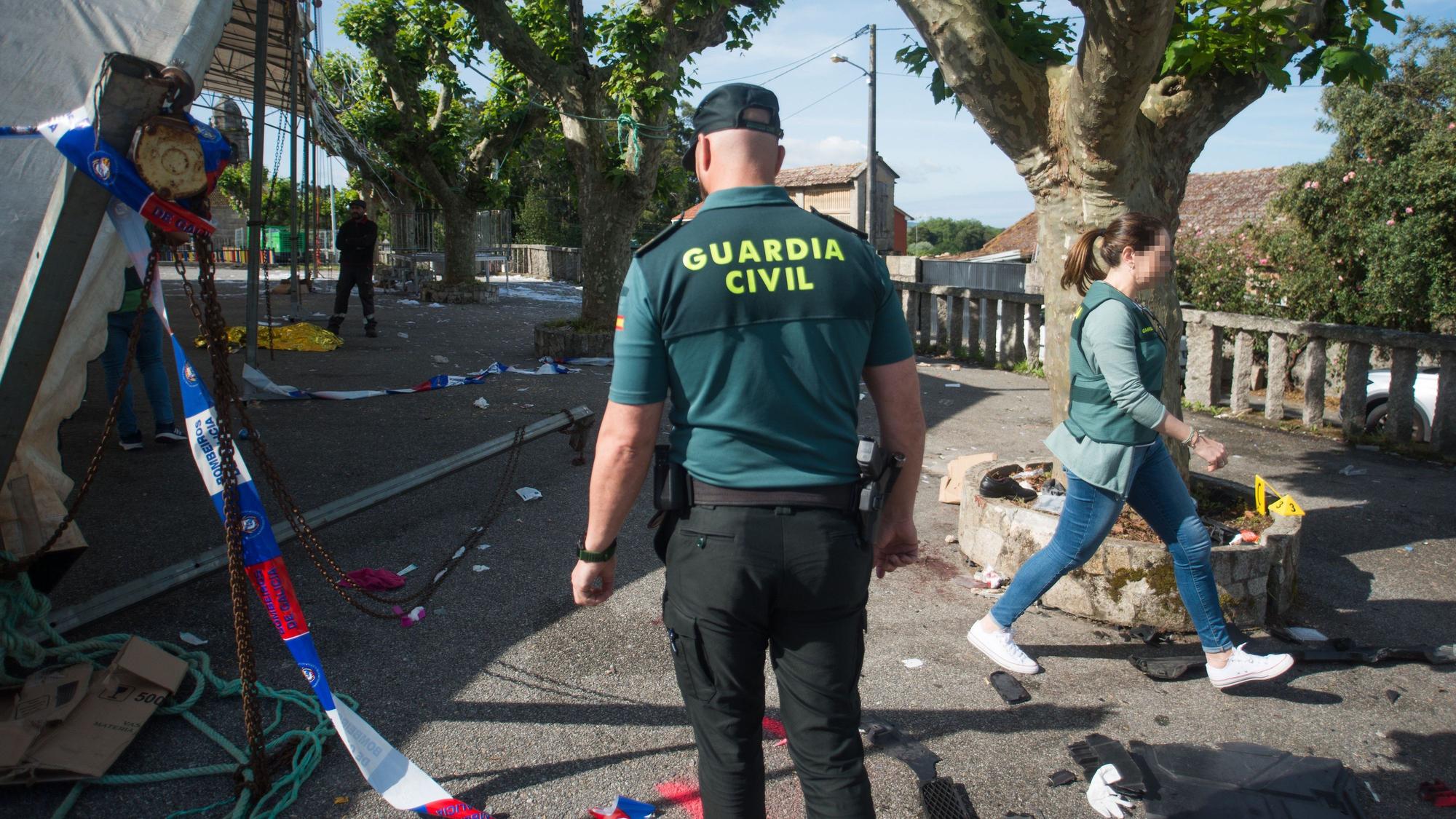 Neben einem Festzelt liegen Banner und Beamte der Guardia Civil gehen das Gelände mit Bäumen ab.