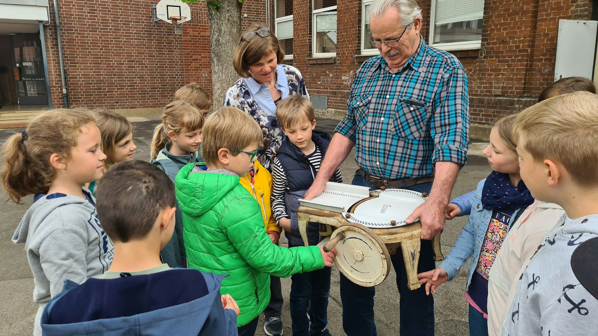 Auf dem Foto ist Landwirt Bruno Franken umringt von Schülern und der Schulleiterin Claudia Neiß zu sehen. Er übergibt die Aufschnittmaschine.