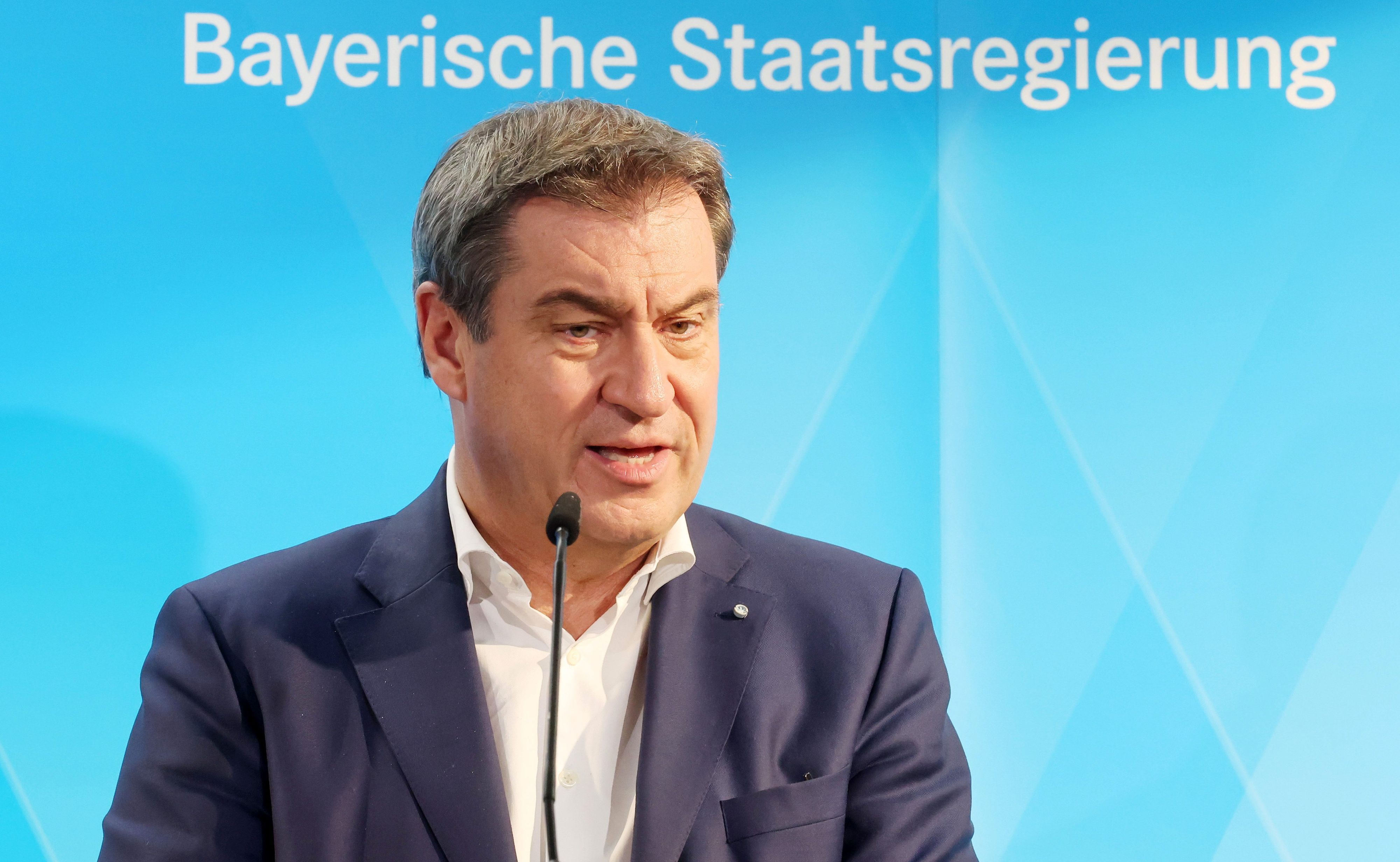 Markus Söder (CSU), Ministerpräsident von Bayern, spricht bei einer Pressekonferenz vor einem blauen Hintergrund mit der Aufschrift „Bayerische Staatsregierung“.