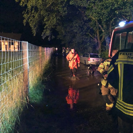 Rückblick auf die Flutnacht. Ein Feuerwehrmann der Feuerwehr Hennef schaut in Richtung eines Mannes mit orangener Jacke.