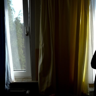 Eine Person steht vor einem Fenster und ist im Gegenlicht nur als dunkle Silhouette erkennbar.