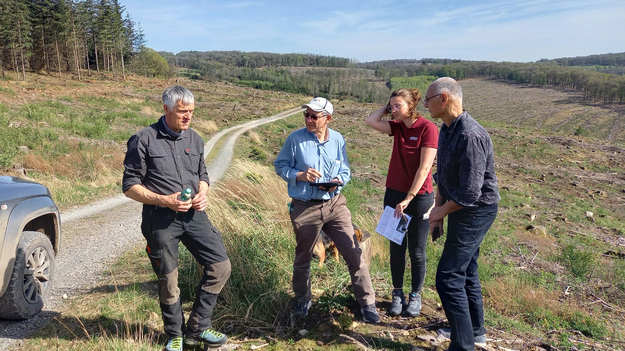 Vor dem Hintergrund abgeholzter Wälder findet ein Gespräch statt.