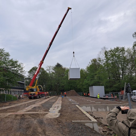 Ein Kran hebt einen Container hoch, der als Ausweichquartier für die Hermann-Voss-Realschule fungieren soll.