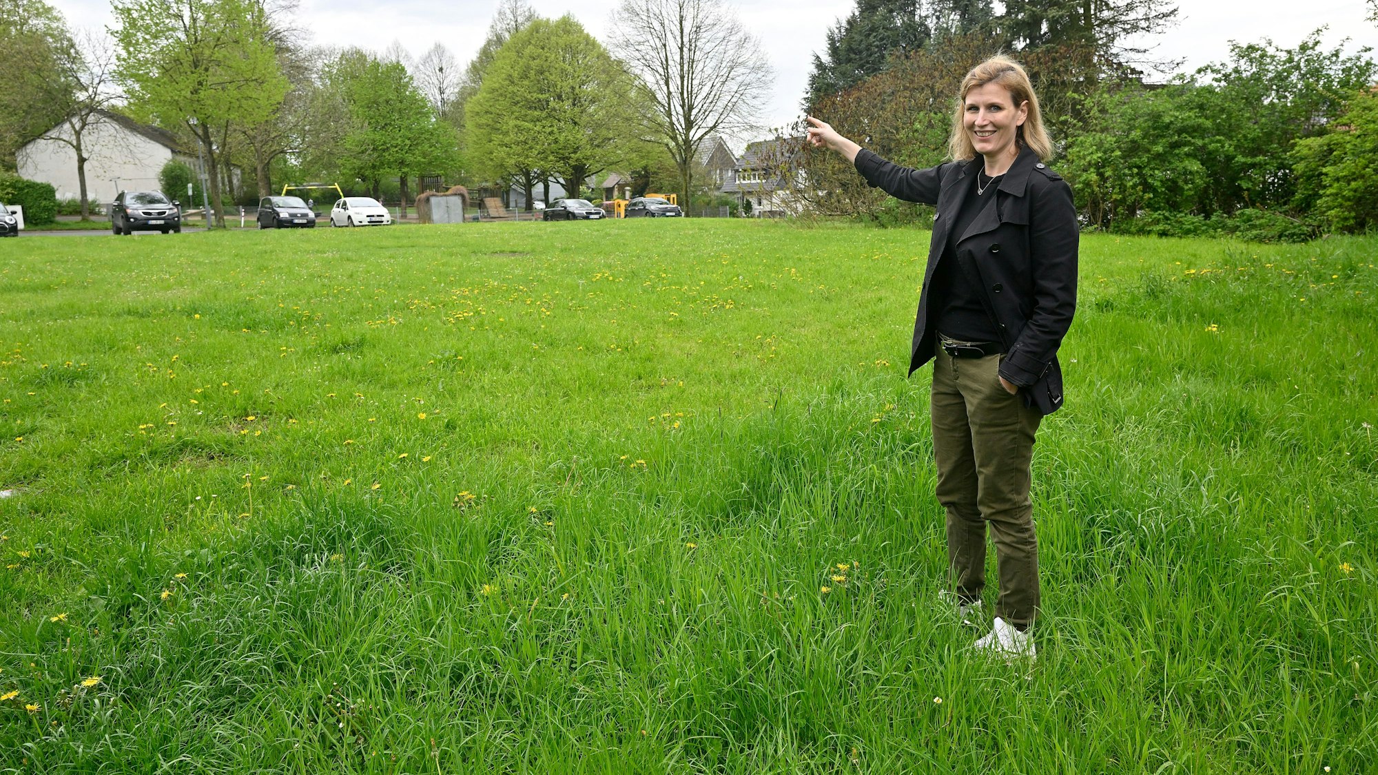 Sabrina Fahlenbock steht auf der Dorfwiese in Moitzfeld und bedeutet mit der Hand, dass hier gut eine Kita gebaut werden könnte.