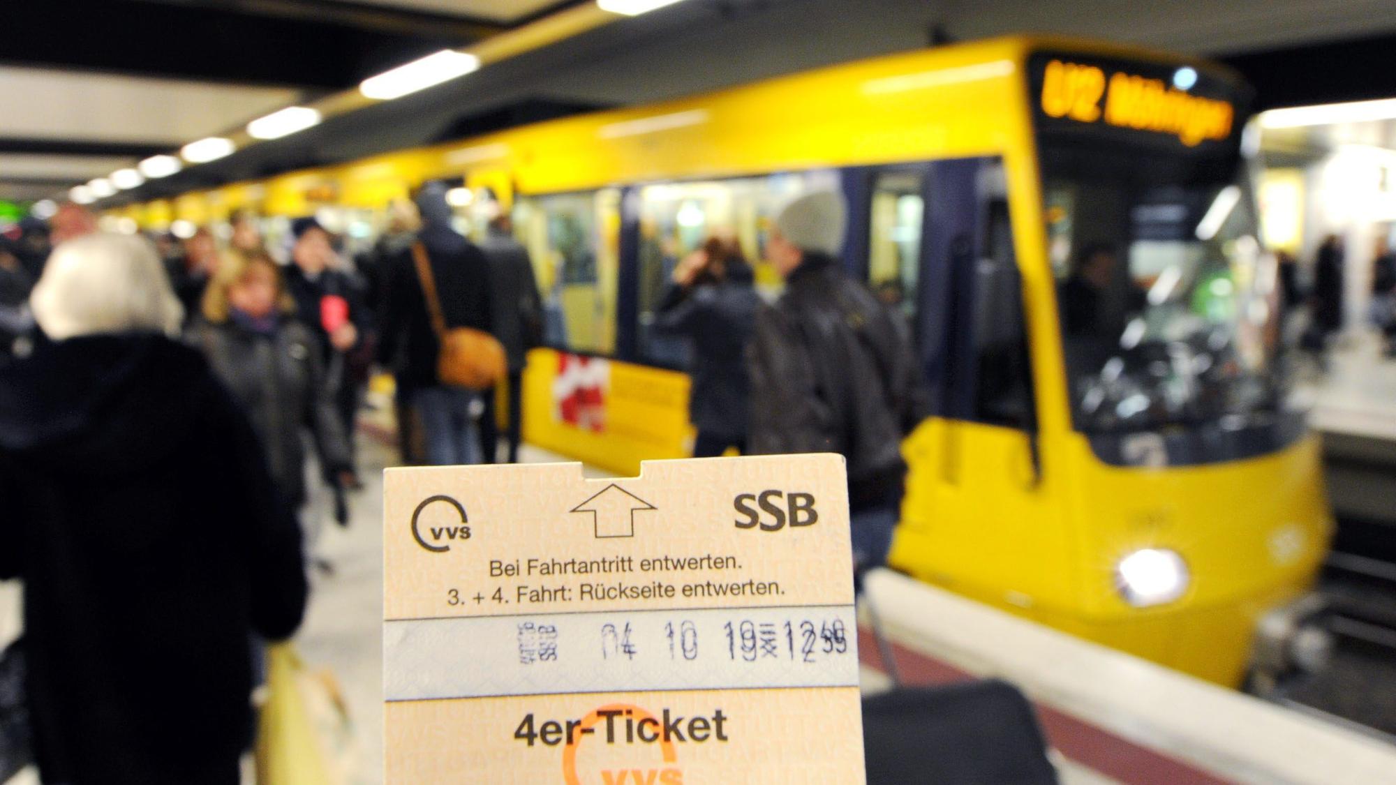 Eine Hand hält am am Hauptbahnhof ein Ticket vor einer Straßenbahn hoch.
