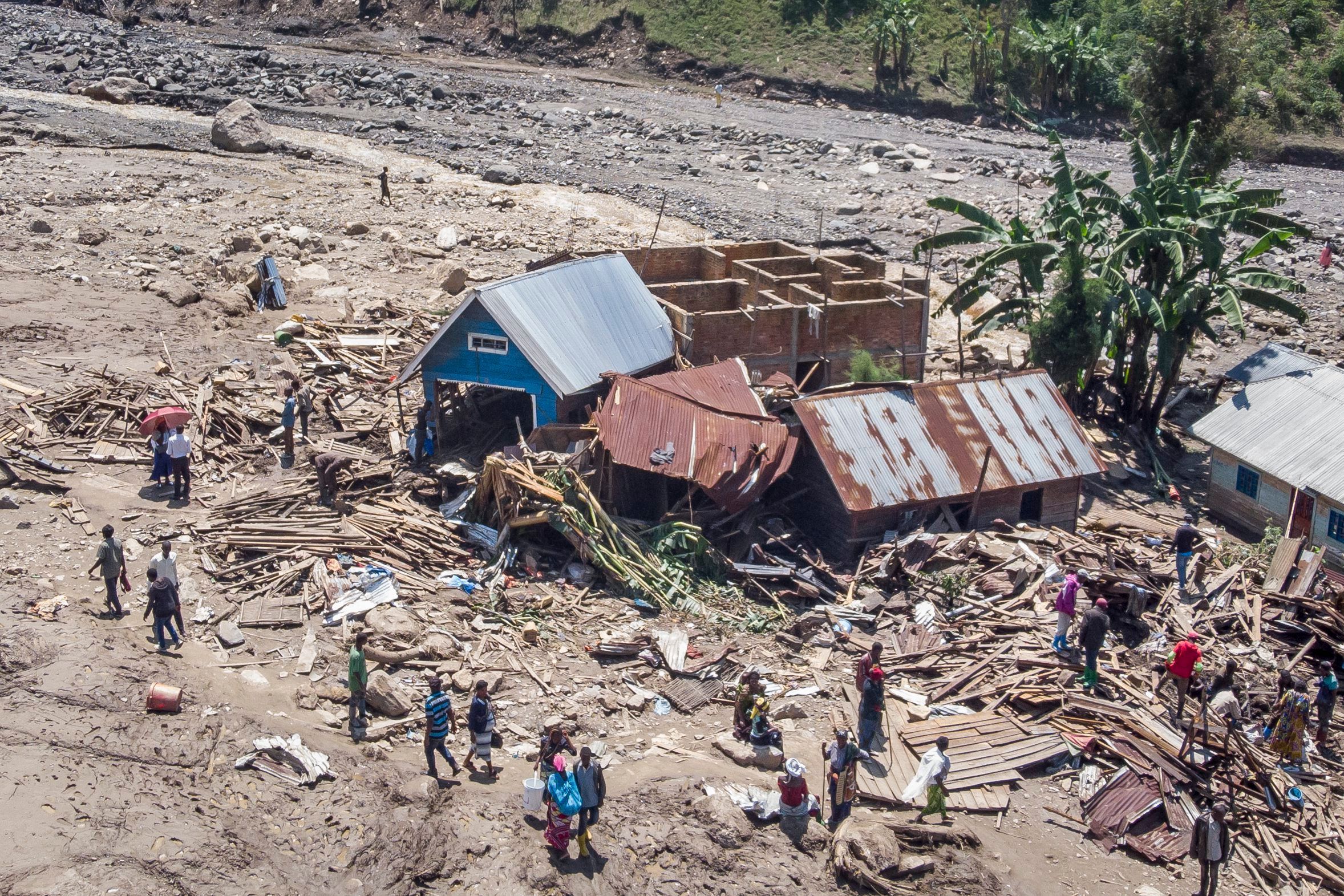 Überlebende gehen inmitten von Trümmern neben zerstörten Gebäuden nach den Überschwemmungen im Dorf Nyamukubi in der Provinz Süd-Kivu im Kongo
