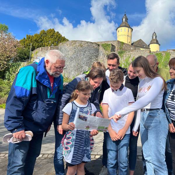Zu sehen ist eine Familie beim Geocaching vor dem Schloss Homburg.
