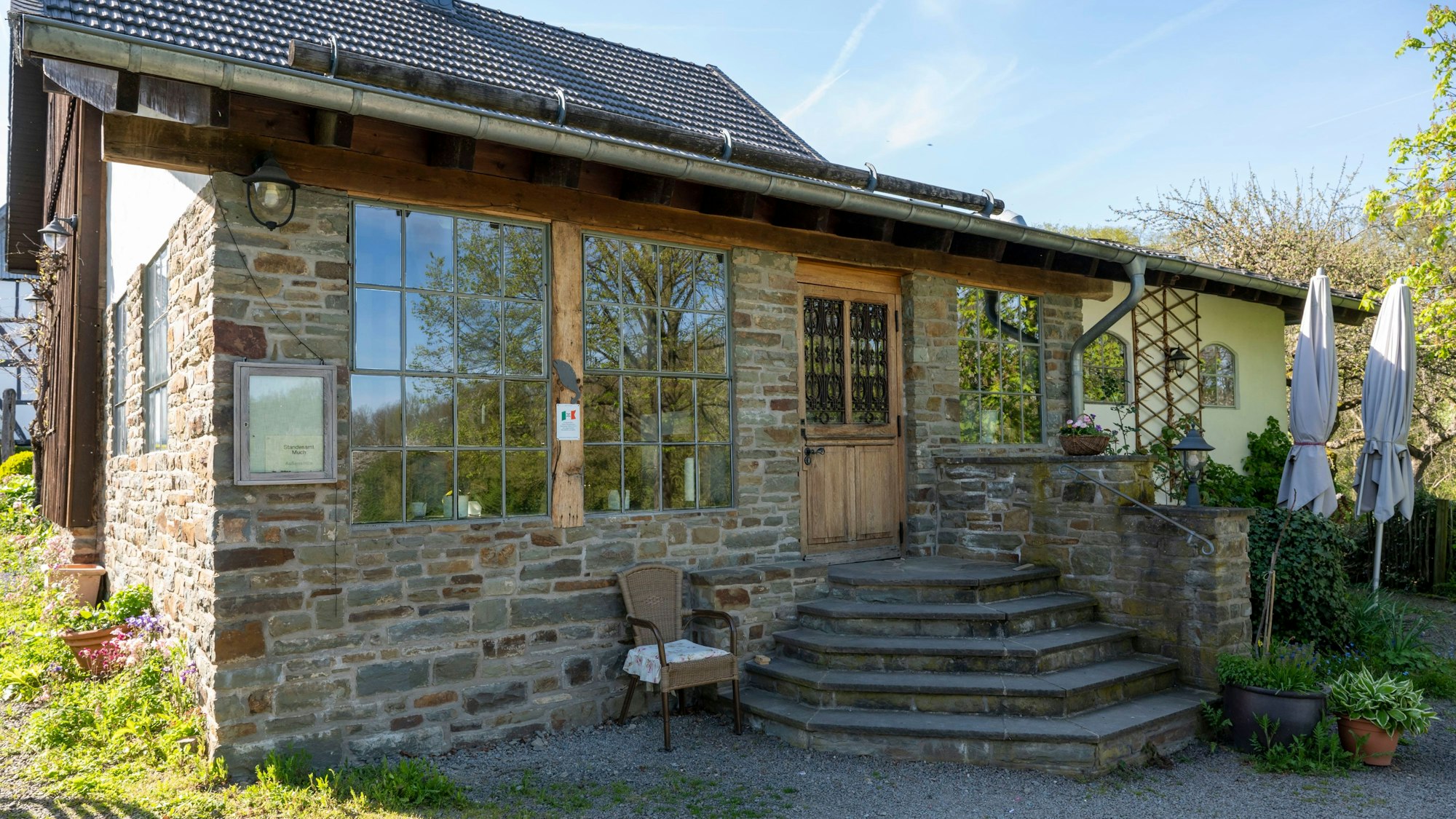Außenansicht eines Hauses mit Steinfassade und einer Treppe, die zu einer Eingangstür aus Holz führt