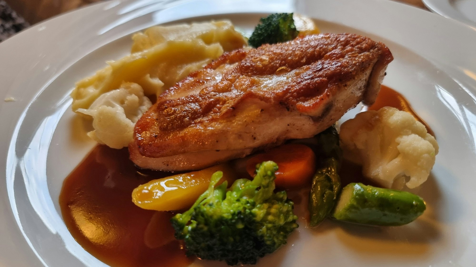 Gemüse, ein Stück Fleisch und Kartoffelpüree angerichtet auf einem Teller