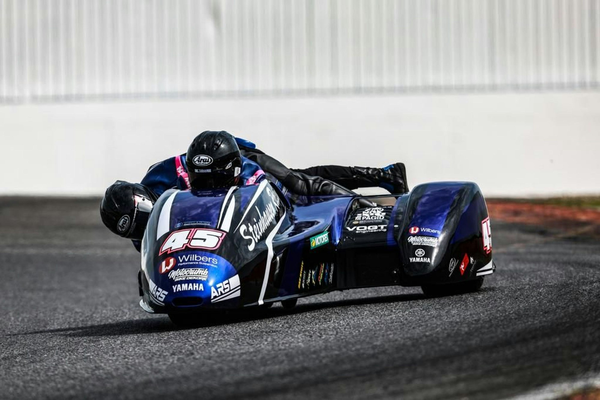 Zwei Motorradrennfahrer auf einer Maschine mit Seitenwagen.