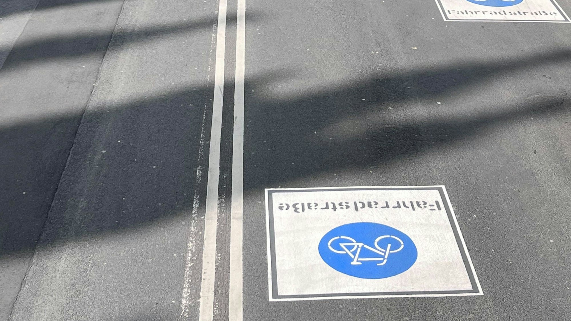 Auf einer Straße ist das Symbol der Fahrradstraße aufgemalt.