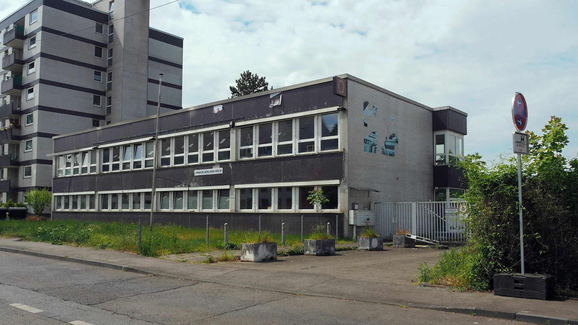 Ein Hochhaus und ein zweistöckiges graues Gebäude sind zu sehen.