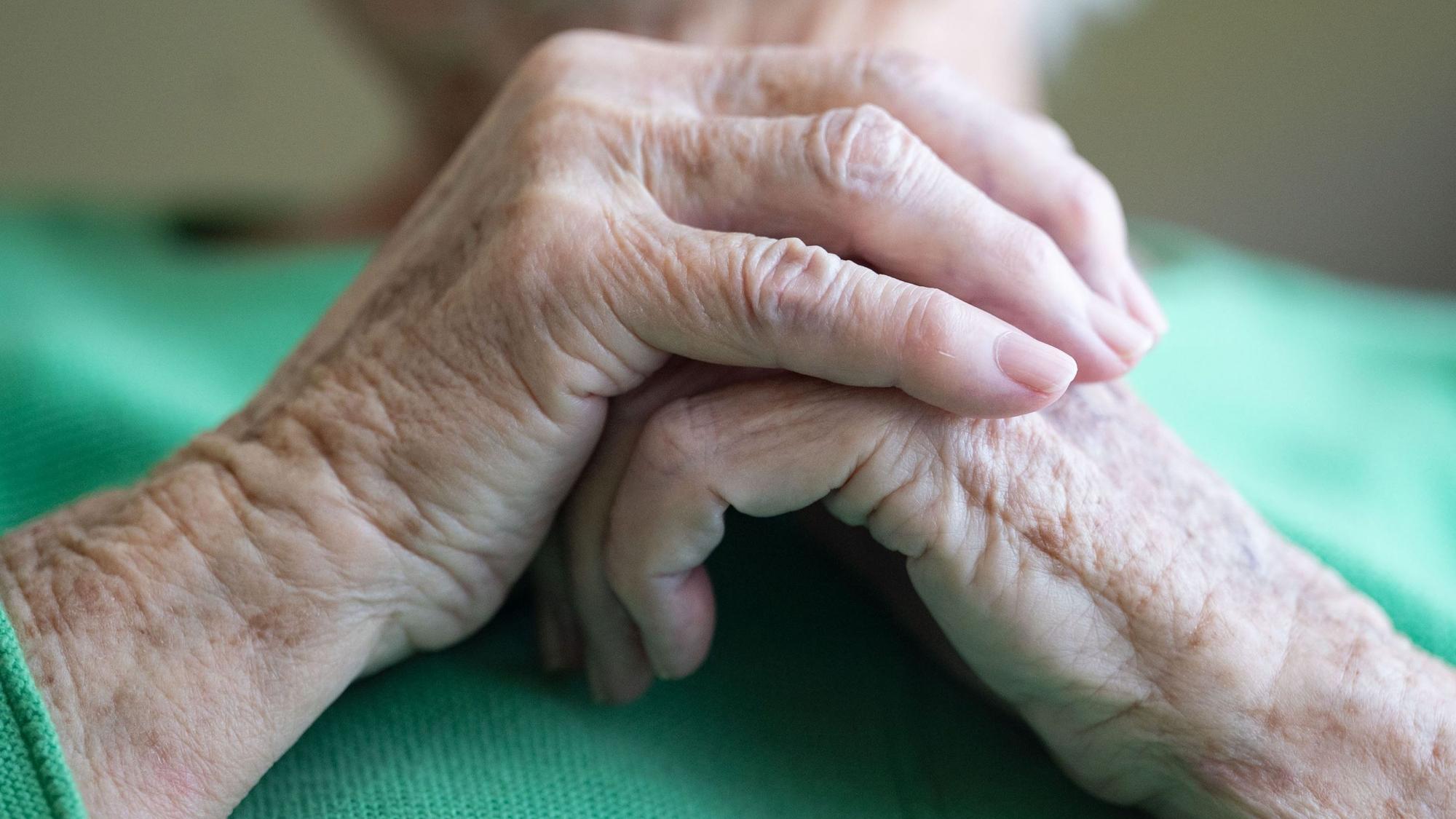 Eine Seniorin faltet ihre Hände.