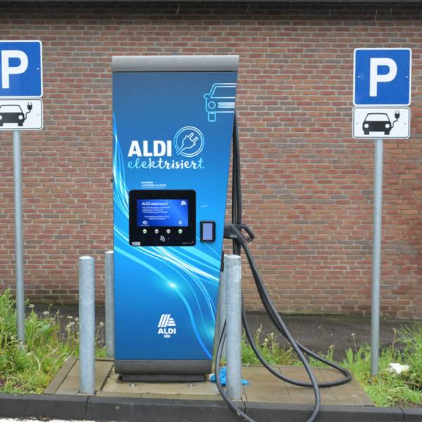 Eine E-Ladesäule mit der Aufschrift „Aldi“ steht vor einer Mauer.