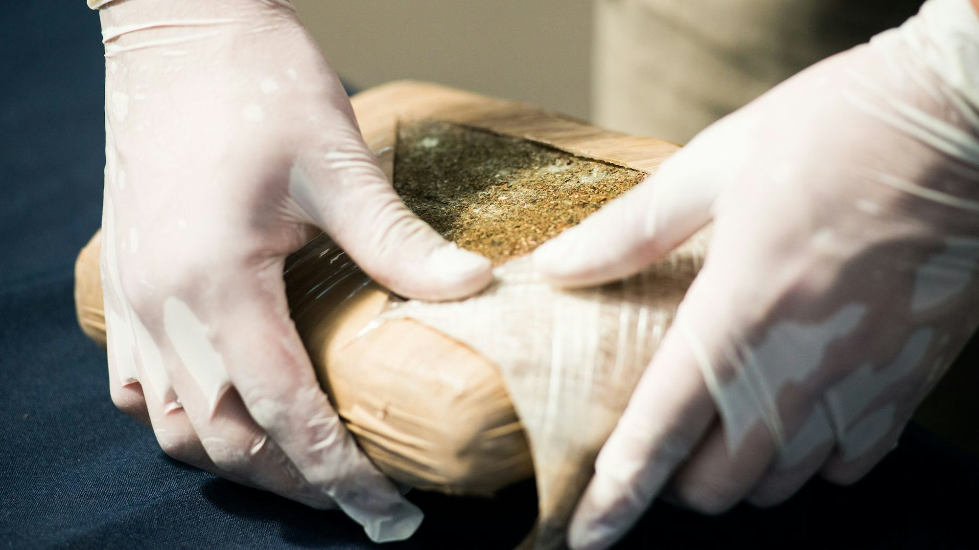 Ein Ermittler öffnet ein Paket mit illegalem Marihuana.