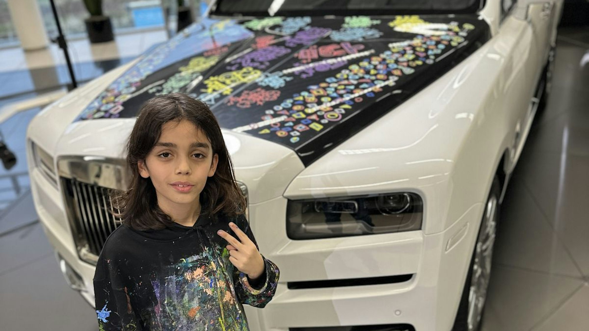 Das Foto zeigt den Zehnjährigen vor einem von ihm bemalten Rolls Royce.