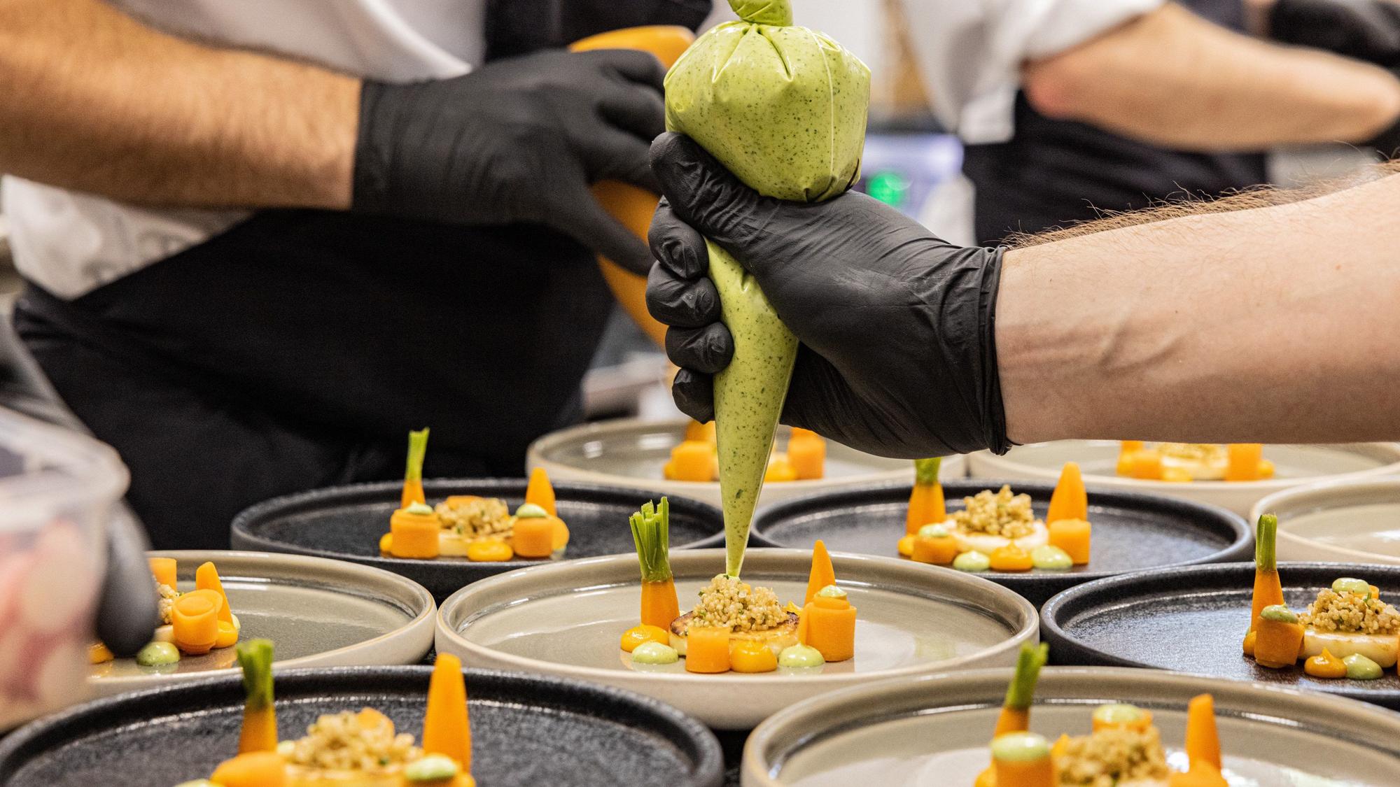 Ein Koch dekoriert bei den Fine Food Days in Köln einen Teller.