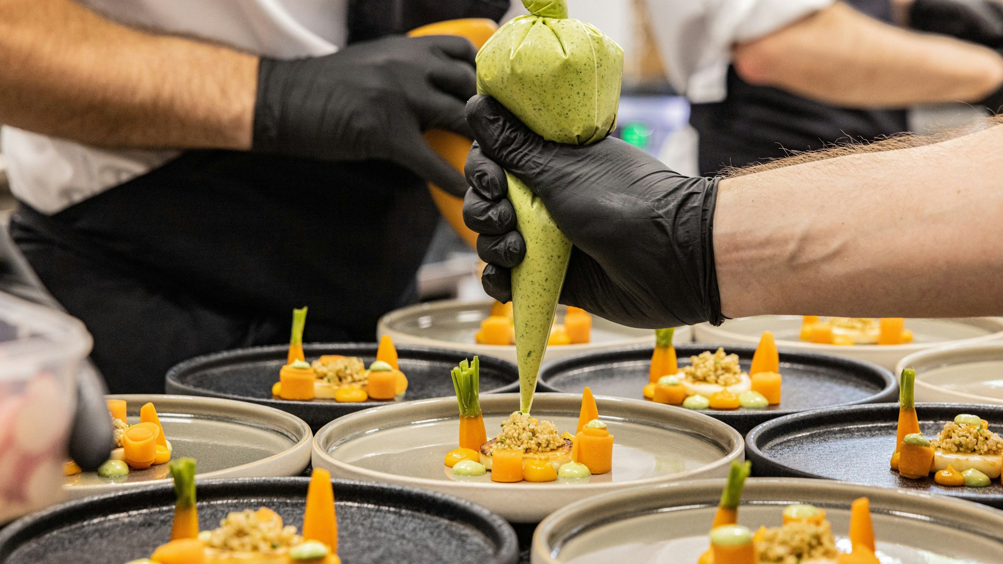 Ein Koch dekoriert bei den Fine Food Days in Köln einen Teller.