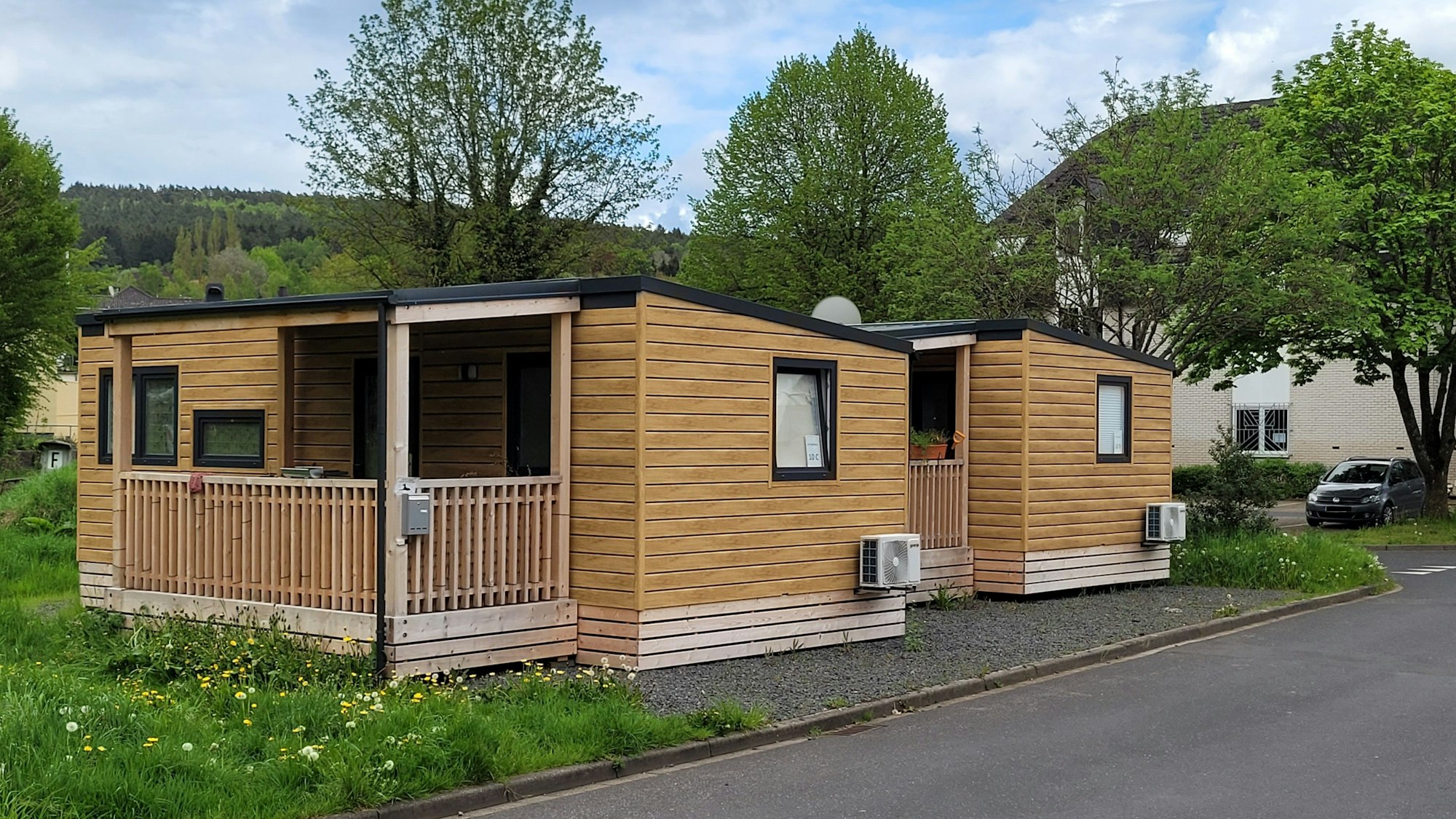 Blick auf zwei Tiny-Häuser, die am Straßenrand stehen.